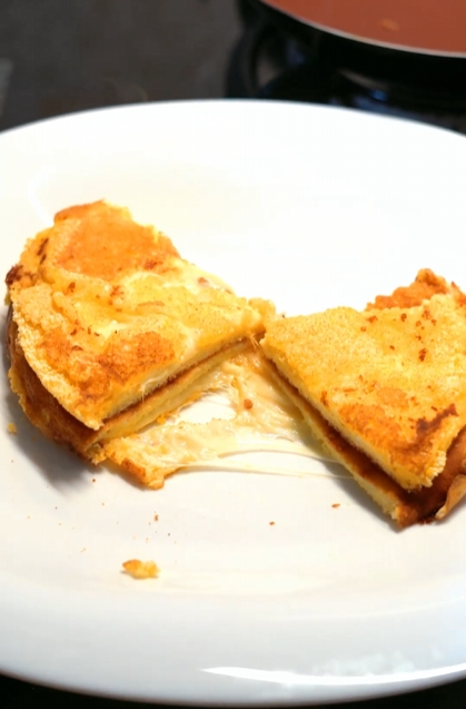 Milhoca com queijo mussarela sobre prato cinza
